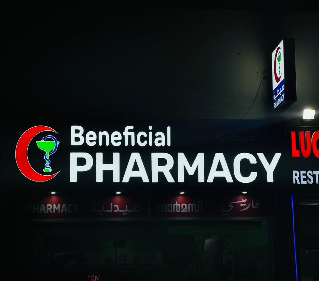 Indoor and outdoor signage for Beneficial Pharmacy in Abu Dhabi, featuring clear branding and prominent display of the pharmacy's name and logo. The signage is strategically placed to attract customers and provide directions to the pharmacy.